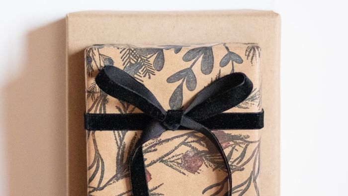 A kraft-paper wrapped corporate gift box tied with a black ribbon